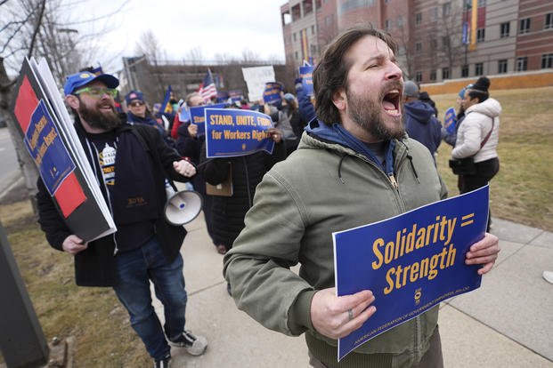 Protesters walk outside the John D. Dingell Veterans Affairs Medical Center