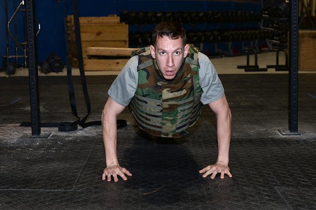 U.S. Navy Cmdr. Jeff Dee, commanding officer of Naval Operations Support Center at Offutt Air Force Base Neb., performs a weight-vest push-up inside the Offutt Air Force Base, Nebraska, Field House gym.