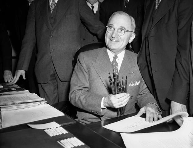 President Harry Truman holds up a handful of pens