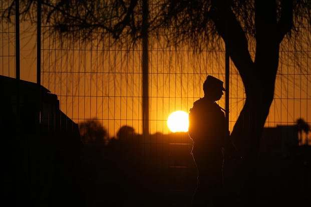 A guardsman stands at a gate to Shelby Park in Eagle Pass, Texas.