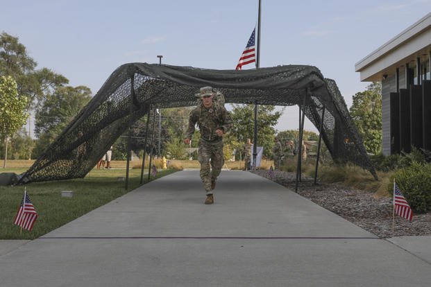 Spc. Tom Hook, a religious affairs specialist attached to the 185th Combat Sustainment Support Battalion, Iowa Army National Guard, crosses the finish line of a 12-mile ruck march event during the 2026 Iowa National Guard Best Warrior Competition at Johnston Town Center, Johnston, Iowa.