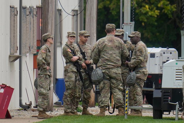 Military personnel in uniform, with the Texas National Guard patch on, are seen at the U.S. Army Reserve Center in Elwood, Ill., a suburb of Chicago. 