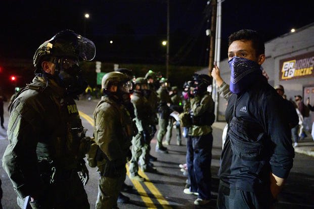 Federal agents stand guard to keep demonstrators away from an Immigration and Customs Enforcement (ICE) facility in downtown Portland, Oregon.
