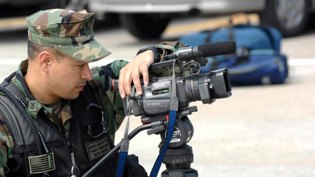 A military camera man, filming.