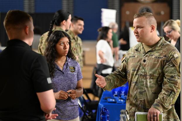 A National Guard members talks to two people at a job fair.