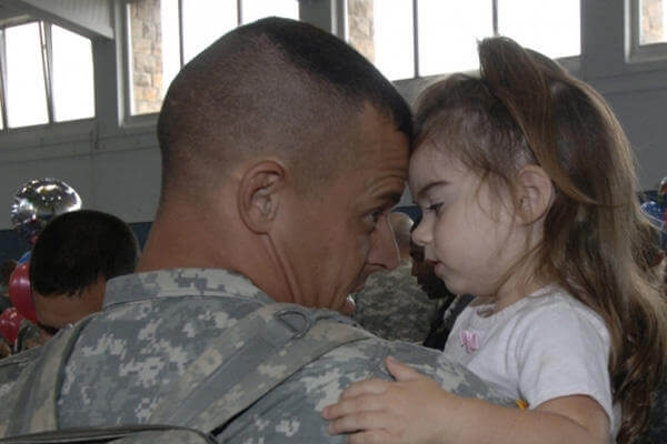 A servicemember hugging his daughter