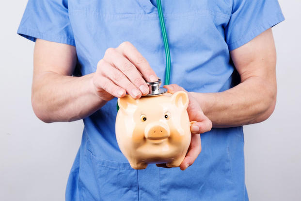 Doctor checking piggy bank with stethoscope