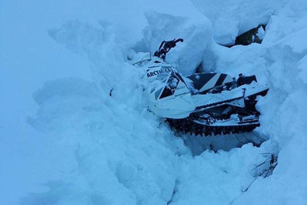 A snowmobile is buried in a snowbank after the operator becomes stranded near Dan Moeller Bowl on Douglas Island near Juneau, Alaska, Jan. 5, 2016.  (U.S. Coast Guard photo)