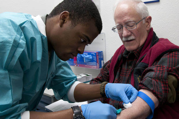 Airman 1st Class Luvens Rorshack draws blood from retired Army chaplain John Rasmussen in the Medical Treatment Facility on F.E. Warren Air Force Base, April 18, 2015. (U.S. Air Force photo/Airman 1st Class Malcolm Mayfield)