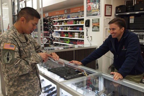 Fort Huachuca Main Post Exchange gun sales supervisor Dawn Deslatte shows Sgt. 1st Class Atthaporm Khaek-on, 309th Military Intelligence Battalion, an American Classic handgun at the PX gun counter (Photo: Gabrielle Kuholski)