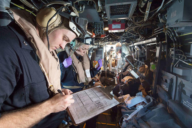 Hospital Corpsman 2nd Class Tracey Farris (left), and an intensive care corpsman aboard USS Kearsarge attached to Fleet Surgical Team 4, record a patient's vital signs during a medical evacuation drill in an MV-22 Osprey. (U.S. Navy/MC3 Tyler Preston)
