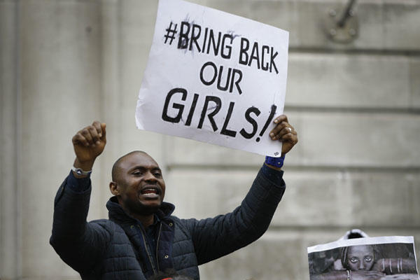A demonstrator holds a banner, during a protest about the kidnapping of girls in Nigeria, near the Nigerian High Commission in London, Friday, May 9, 2014. (AP Photo/Kirsty Wigglesworth)
