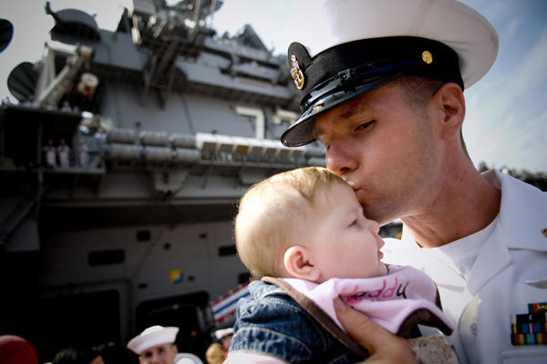 A sailor holding and kissing his child.