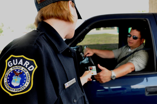 A civilian security guard checks an Air Force base commuter's ID before waving him on. Starting July 10, military bases in eight more states will no longer accept driver's licenses as official identification. (US Air Force photo/Anthony Jennings)