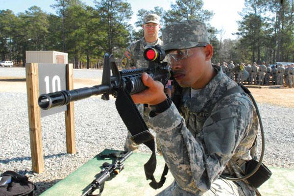 Army recruit during basic training aims a rifle.
