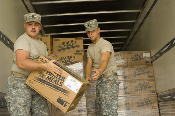 Two soldiers moving boxes in a truck.