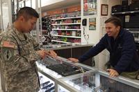 A Post Exchange gun sales supervisor shows a solider an American Classic handgun at the PX gun counter at Fort Huachuca. (U.S. Army Gabrielle Kuholski)