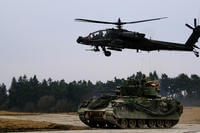 An M2 Bradley fighting vehicle and an AH-64 Apache helicopter secure an area during a Combined Arms Live Fire Exercise (CALFEX) in Grafenwoehr Training Area, Germany in March 2018. (US Army photo/Hubert Delany III)