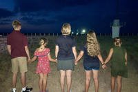 family holding hands standing in a field