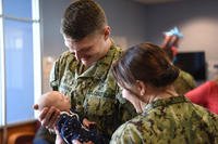 dual military couple looking at new baby