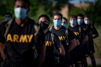 Soldiers stand in formation while wearing masks and maintaining physical distancing.