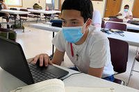 student sitting at desk with a mask on