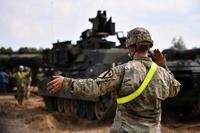 A U.S. Army soldier guides an M1 Abrams Main Battle Tank to a fueling station in Poland.