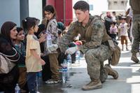 A Marine provides water to a child during evacuation at the airport in Kabul