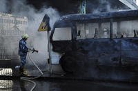 Syrian firefighter extinguishes a burned bus at the site of a deadly explosion, in Damascus, Syria