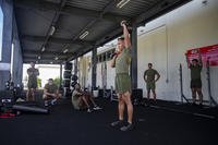 A Marine performs a military press with kettlebells.