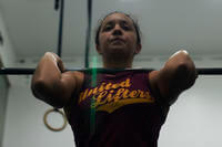 An airman prepares to do a barbell shoulder press.