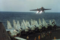 A U.S. Navy F-14 lifts off over a row of A7 Corsairs