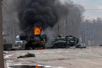 A Russian armored personnel carrier burns amid damaged and abandoned light utility vehicles after fighting in Kharkiv, Ukraine