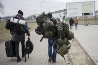 man carries combat gear as he leaves Poland to fight in Ukraine, at the border crossing in Medyka