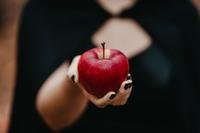 poison red apple held out by woman with black fingernails