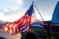 american flag waves from black pickup truck