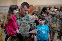 A soldier looks at paperwork while reuniting with his family.