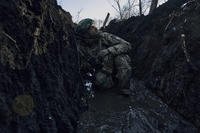Ukrainian soldier takes cover in a trench under Russian shelling on the frontline close to Bakhmut