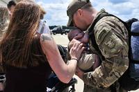 An airman returning from deployment kisses his newborn son.