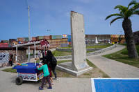 A family pushes a snack cart past a slab of the Berlin Wall in Tijuana, Mexico.