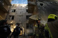 Israeli security forces inspect a damaged building after it was hit by a rocket from the Gaza Strip