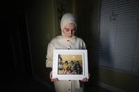 Maryam Kamalmaz holds a photo of her father with some of his 14 grandchildren in Grand Prairie, Texas