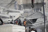 Emergency services work at a building hit by an air strike in Damascus, Syria.