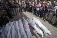 Mourners pray over the bodies of Palestinians who were killed in an Israeli airstrike.
