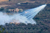A shell that appears to be white phosphorus from Israeli artillery explodes over a house