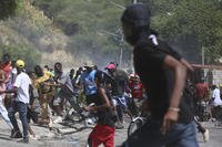 People run from tear gas fired by police in Port-au-Prince, Haiti