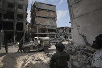 Israeli soldiers take position next to buildings destroyed by the Israeli military in the Gaza Strip