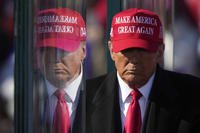 Donald Trump is reflected in the bullet proof glass at a campaign rally