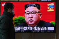 A man watches a television screen showing news footage of North Korean leader Kim Jong Un