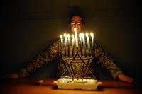 Capt. Andrew Cohen, a chaplain, stands behind a lit menorah during the 8th day of Hanukkah at Joint Base Balad, Iraq, Dec. 28, 2008. (Senior Airman Jason Epley/U.S. Air Force photo)